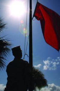 A Marine raises a red flag outside of Headquarters and Service Battalion, indicating the outside temperature is 88 to 89.9 degrees. (photo by Cpl. Sarah Fiocco)